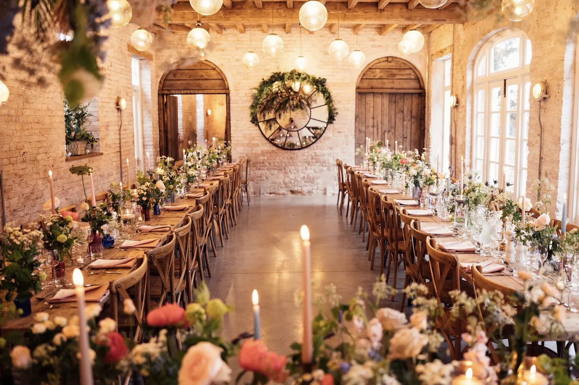 The Coach House at Iscoyd Park laid for a wedding breakfast, with candles and flowers along two long tables.